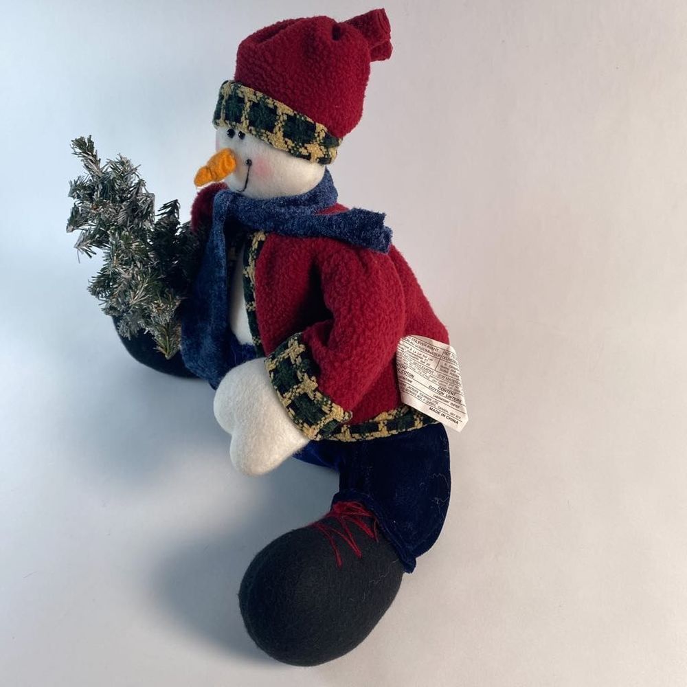 Plush Snowman holding artificial snow flocked tree.